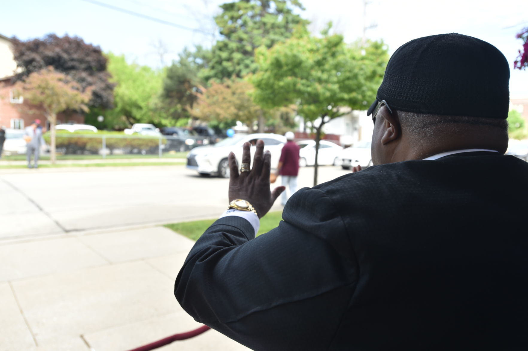 Rev. Bishop Kirby waves at first vehicles of the motorcade